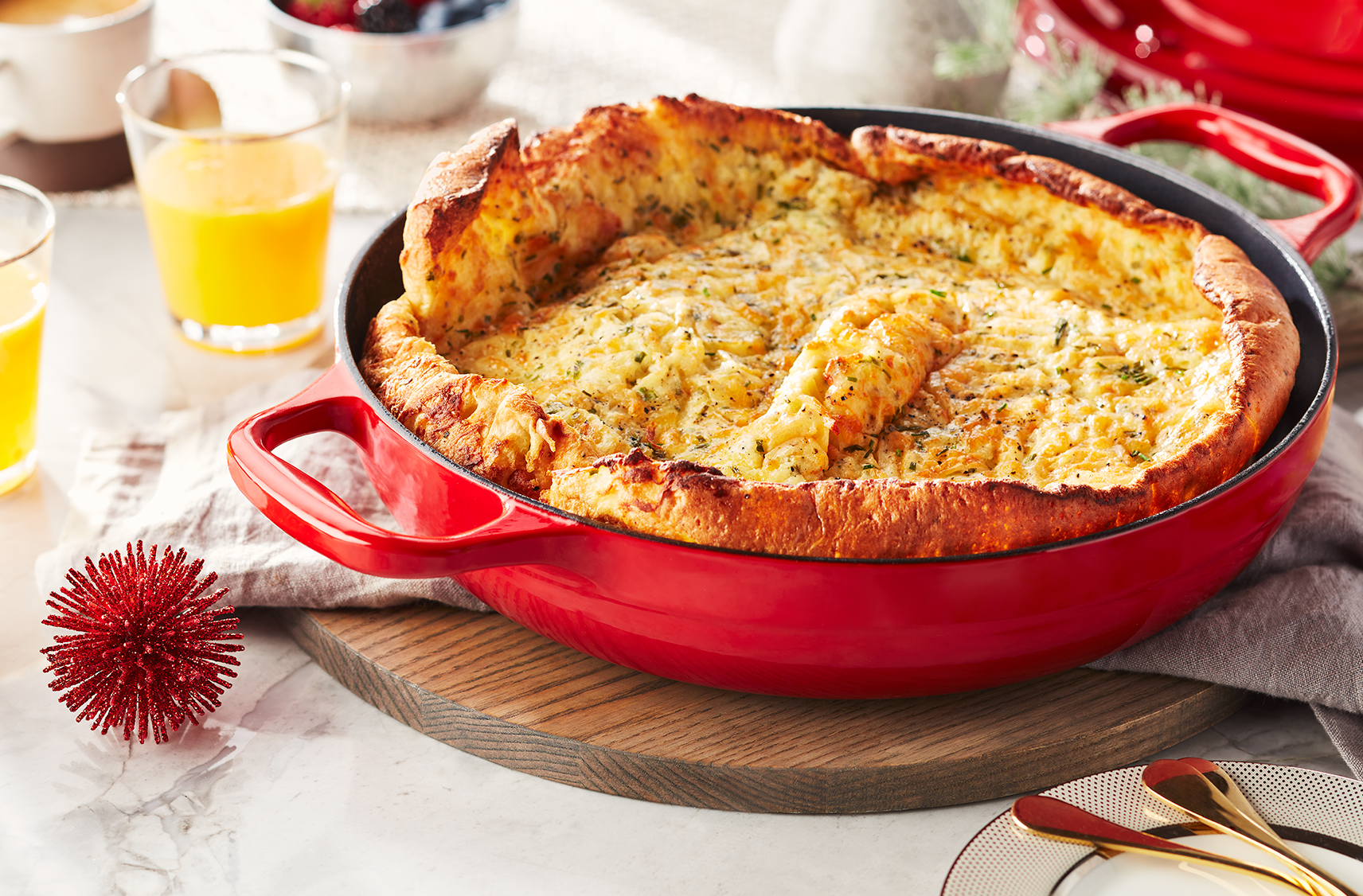 A dutch pot filled with a savoury cheddar and chive casserole dutch baby on a cutting board ready to be served