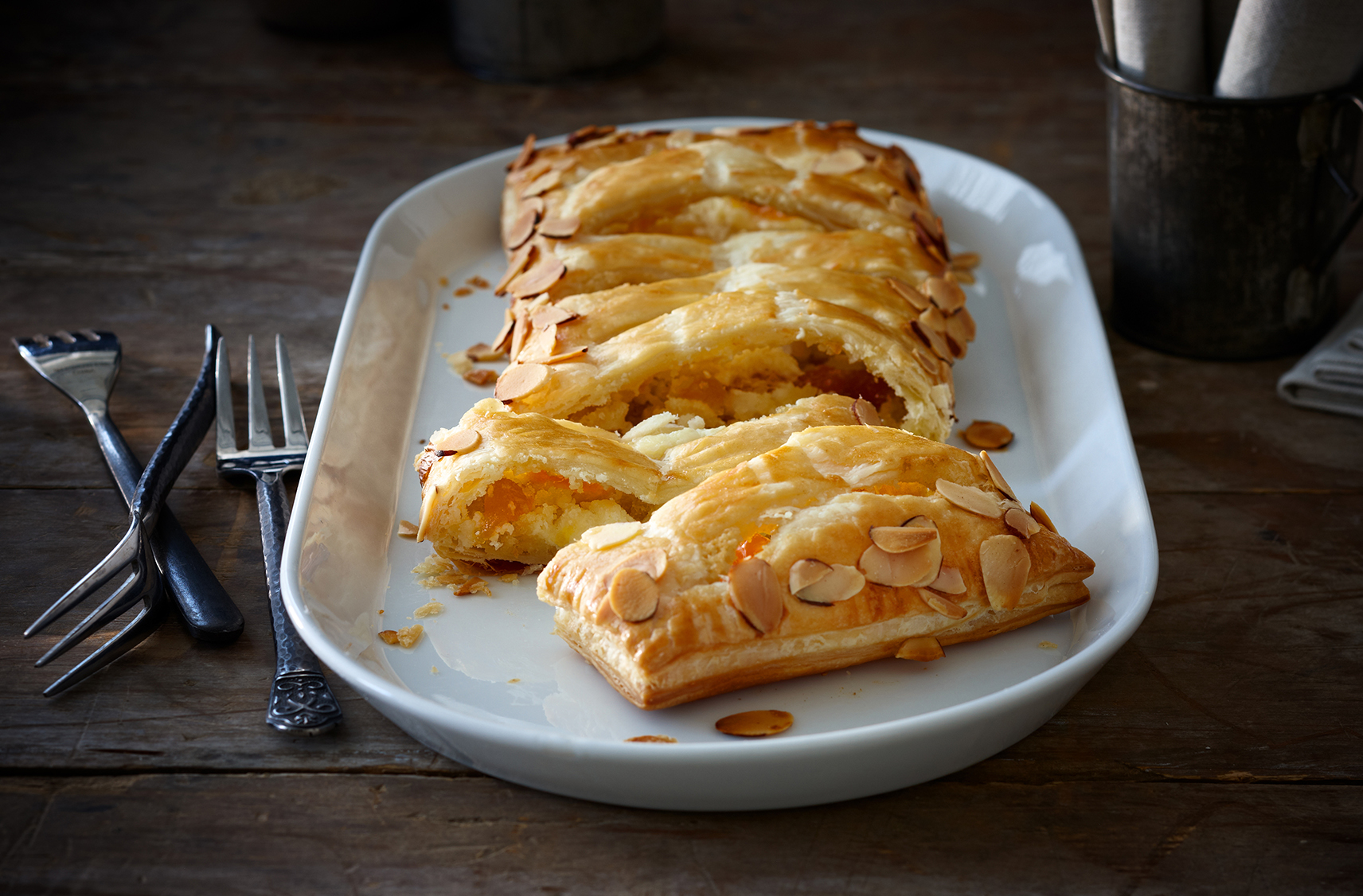 A whole peach and almond Jalousie cut into slices on a platter