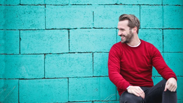 Smiling man leaning on a blue wall