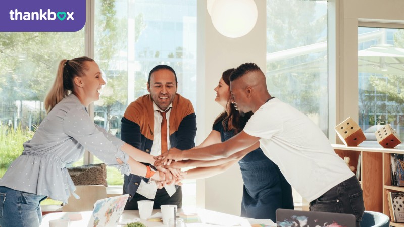 Smiling multiracial coworkers with hands together in office