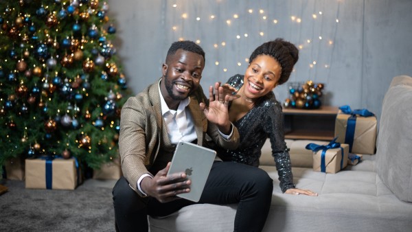 A couple on a video call in front of a Christmas tree