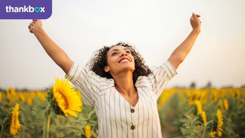 Woman making a victory pose in a sunflower field