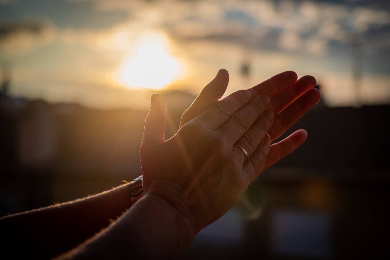 Hands clapping with sunset behind