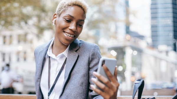 Young ethnic female having video call on city street