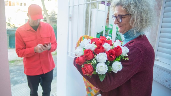 Woman receiving a bouquet of flowers from the deliveryman