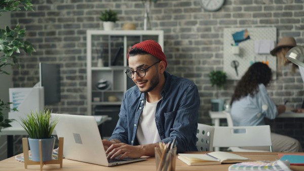 Man wearing a red hat and working on his laptop