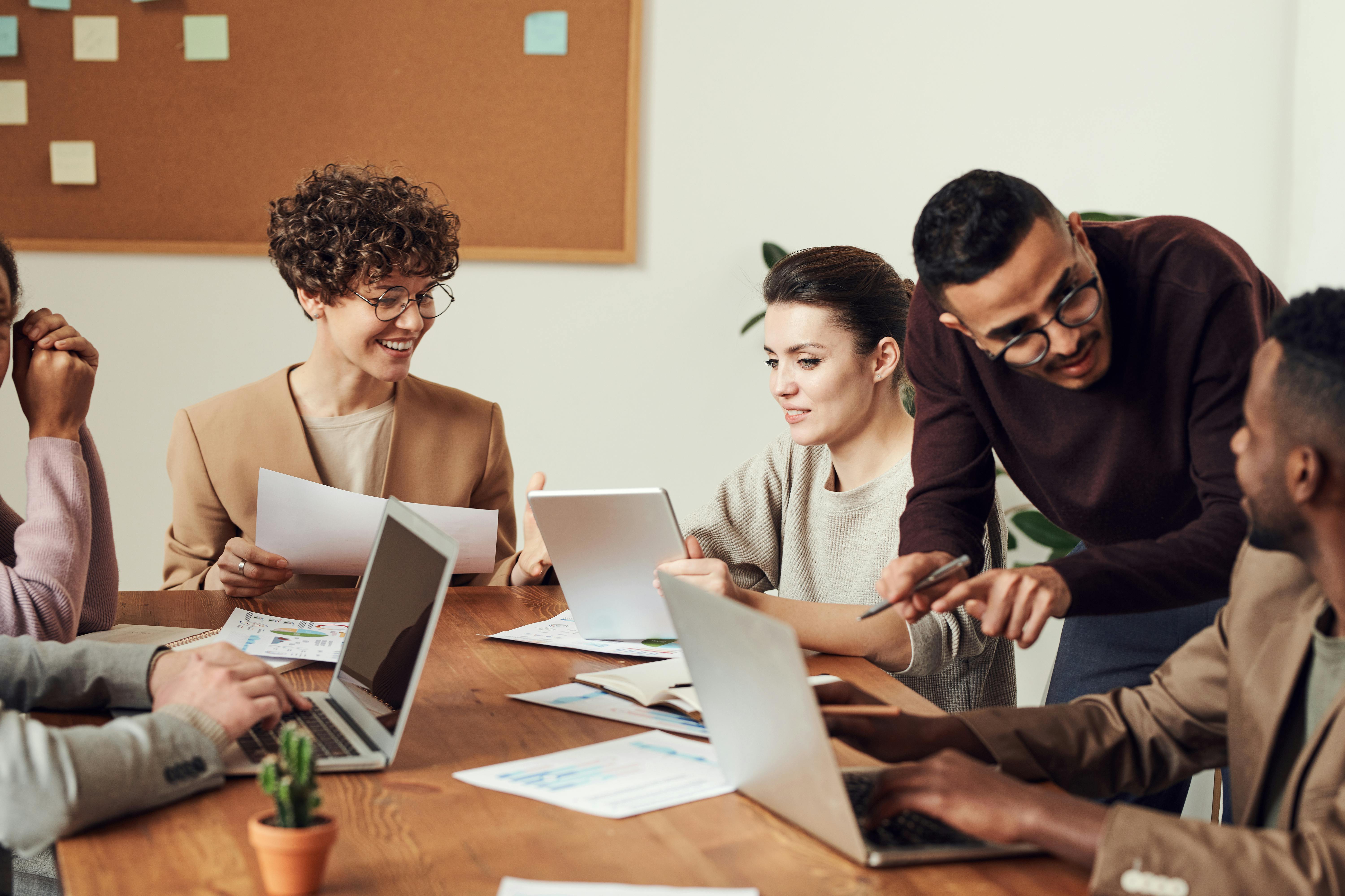 A group of colleagues are gathered around a desk at work