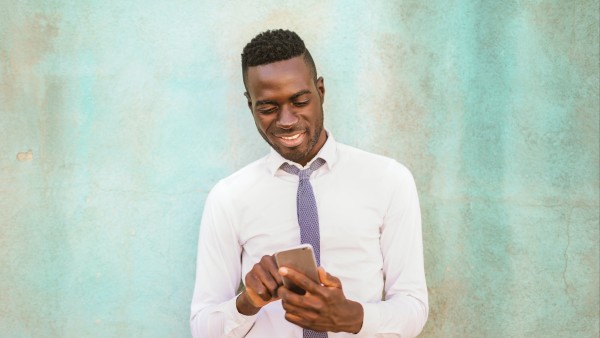 Smiling man in a white shirt holding a smartphone