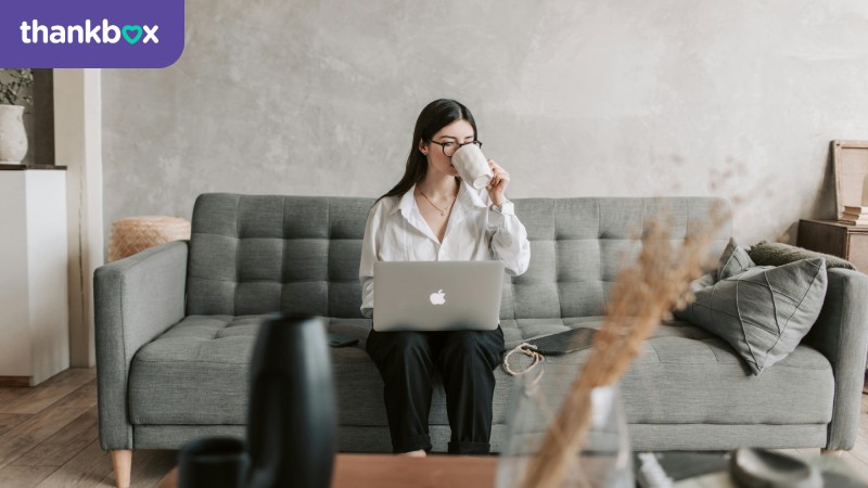 Woman drinking coffee while working on a laptop