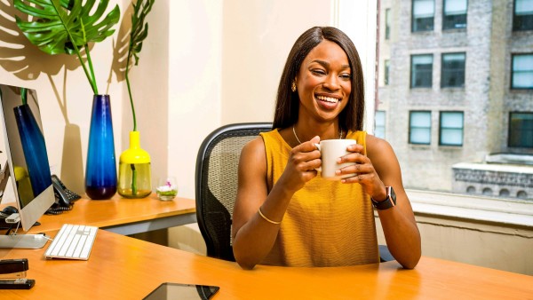 Woman holding white ceramic mug at a desk