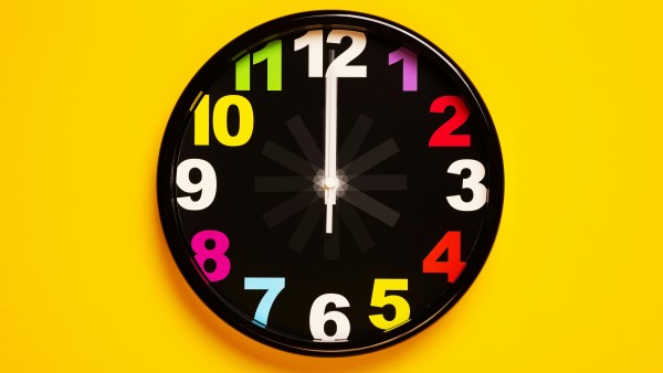 Black clock on a yellow wall