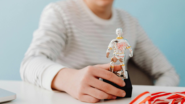 Boy Holding Silver Figurine of Football Player
