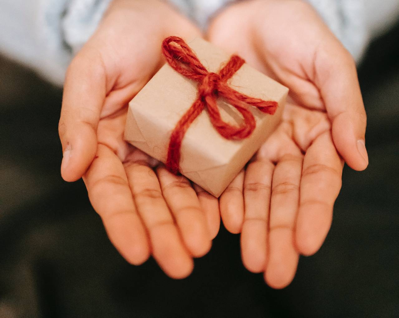 Hands holding small gift with string bow