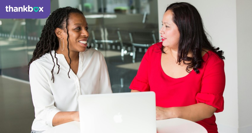 Woman in red shirt sitting beside a woman in a white shirt