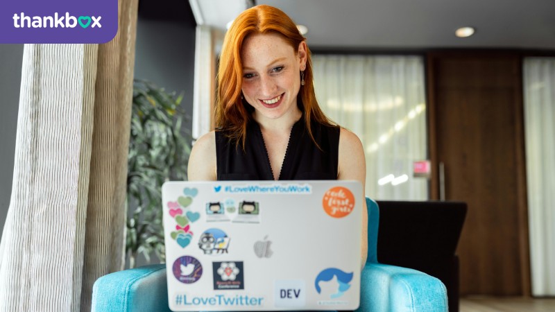 Woman sitting on a blue chair while using a laptop