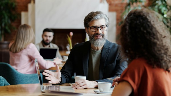 Bearded man in a coffee shop talking to a woman