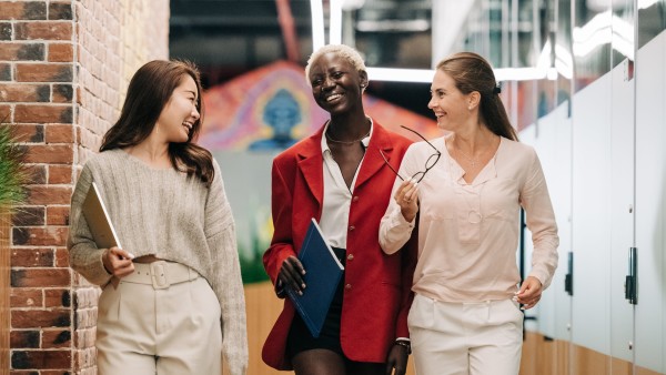 Diverse businesswomen smiling and walking together in a modern workplace