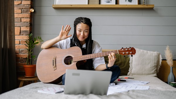 Asian girl holding a guitar in an online lesson