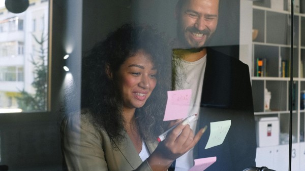 Happy colleagues looking at sticky notes