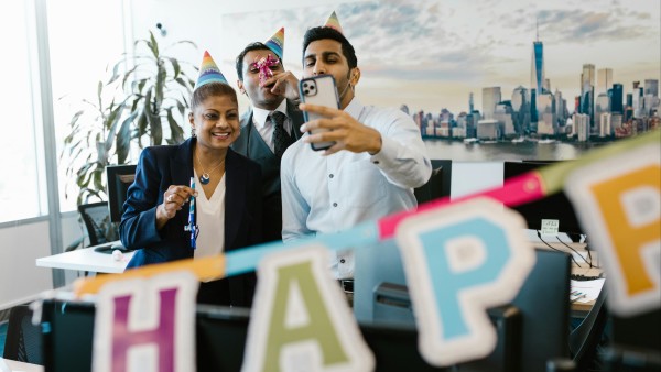 Employees celebrating and taking selfies in an office