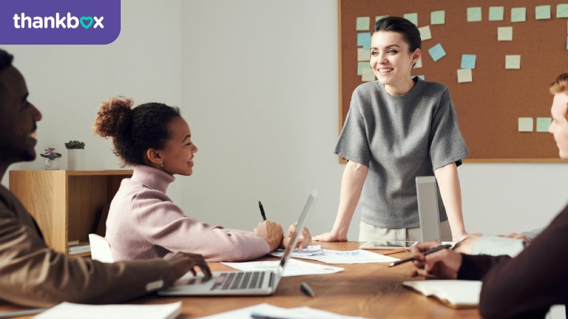 A businesswoman in a grey shirt talking with her colleagues