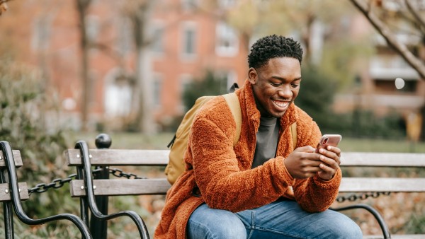 African American man sitting on a bench in a park