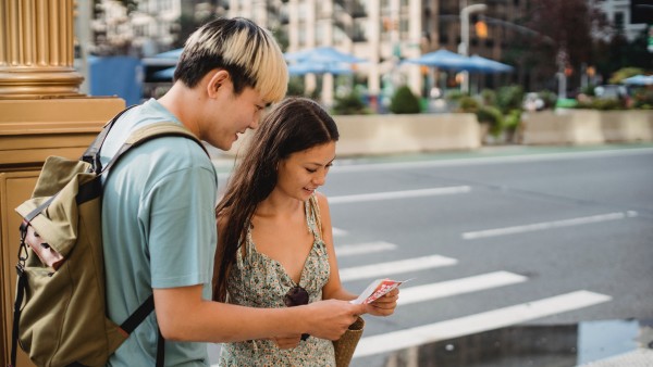 Travelling couple standing on a sidewalk with map