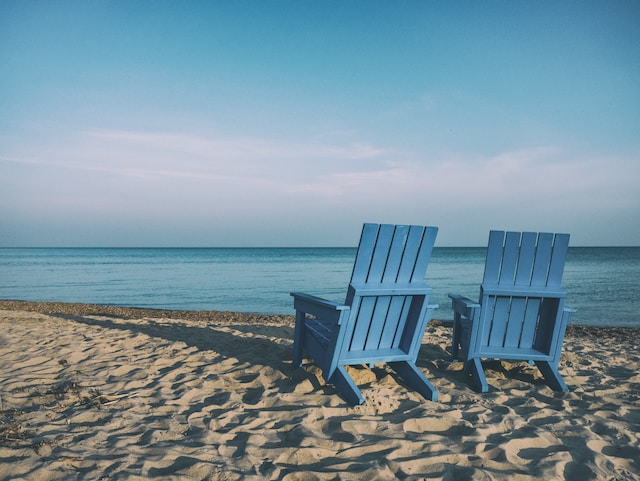 two blue beach chairs near body of water
