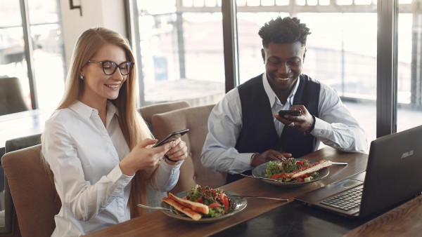 Cheerful diverse colleagues taking photos of their food