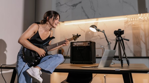 Woman playing an electric guitar in front of a laptop