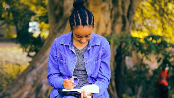 woman reading book while sitting at bench