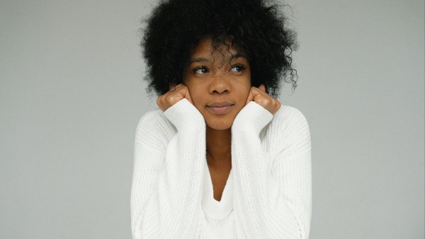 Woman in white sweater holding her chin