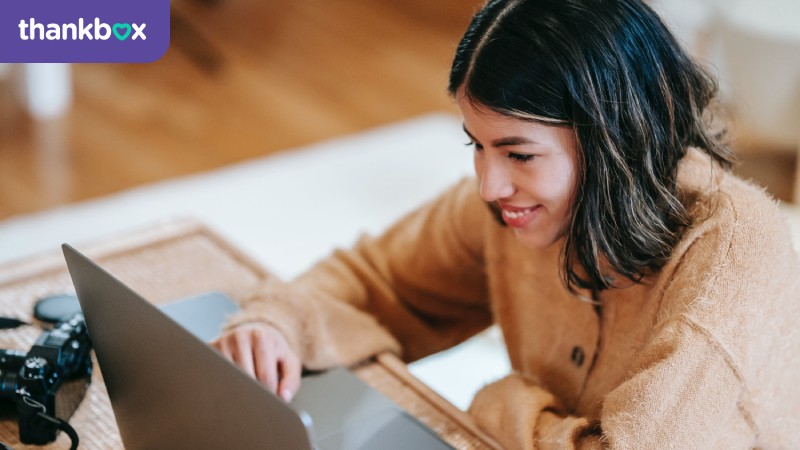 Cheerful female photographer using laptop at home