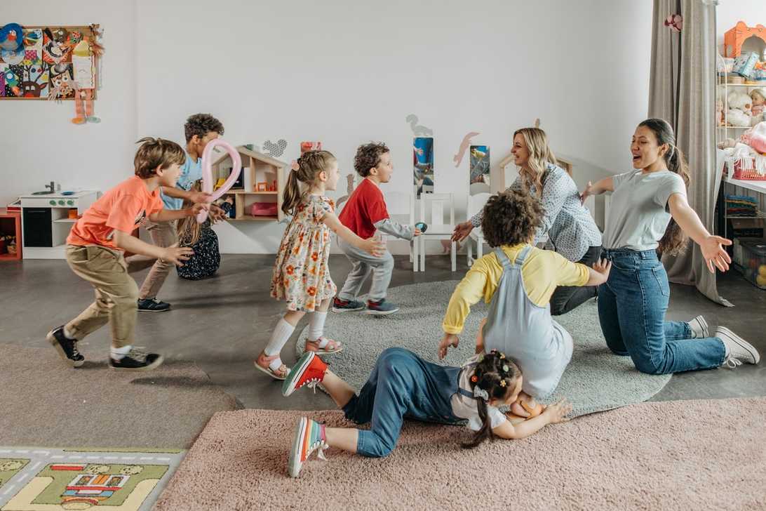 Teachers playing with happy young children in class.