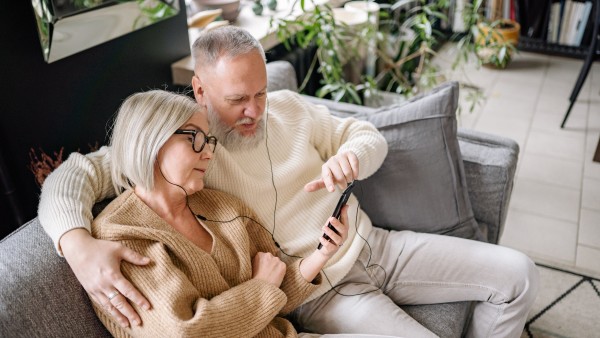 A couple sharing earphones while using the same smartphone