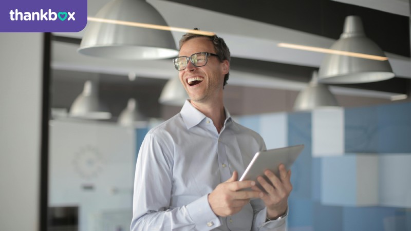 Laughing Man in White Shirt Carrying a Tablet