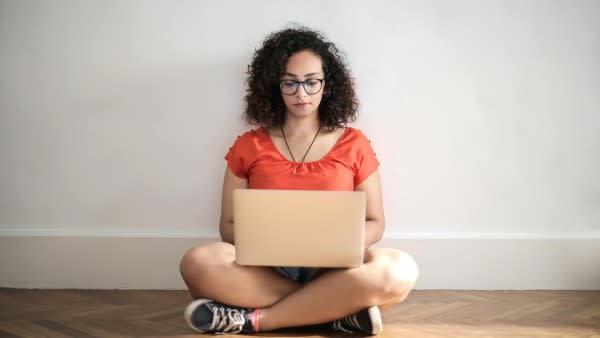 Woman sitting on a wooden floor using a laptop