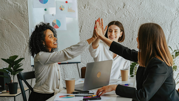 Women sitting at a table giving high fives