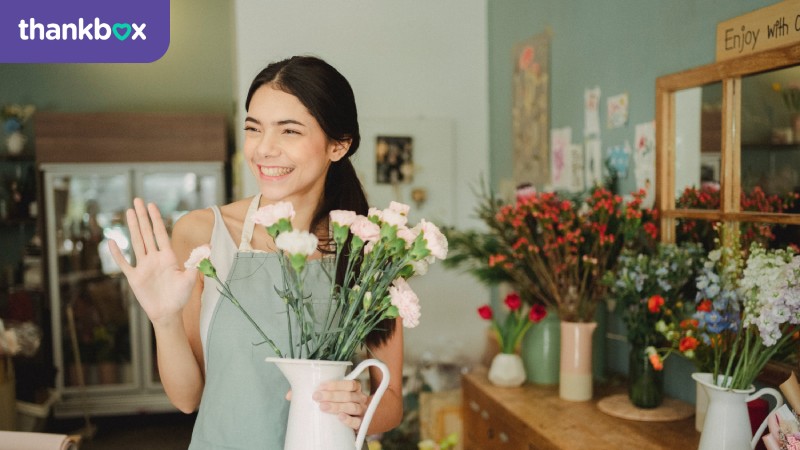 Female florist holding a vase with flowers in a shop