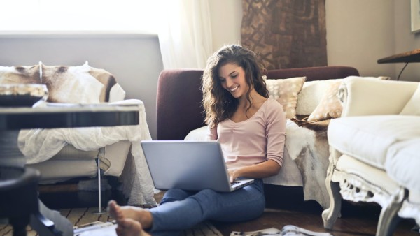 Smiling woman sitting on the floor while using a laptop