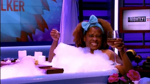GIF of happy lady enjoying wine and chocolates in a bubble bath