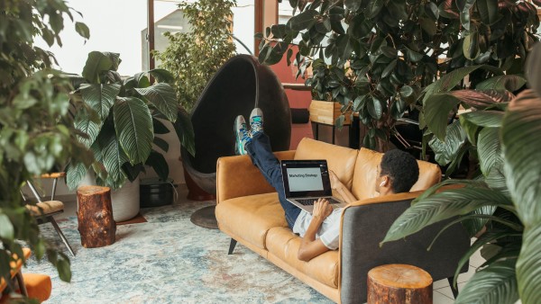 A man using a laptop while lying on the couch