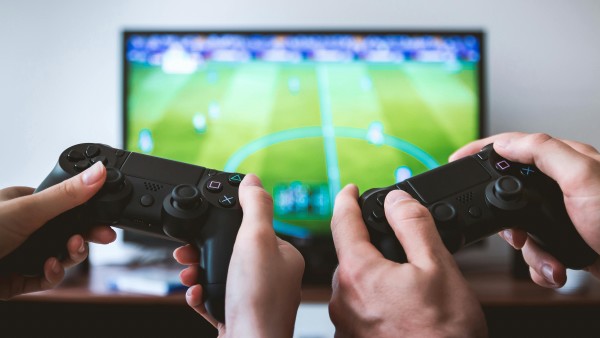 Two people holding joysticks and playing football