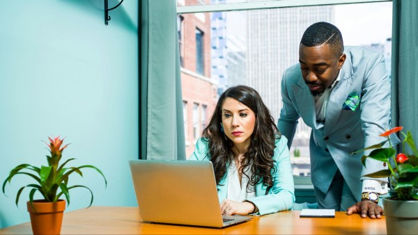 Man and a woman in turquoise suits looking at a laptop screen