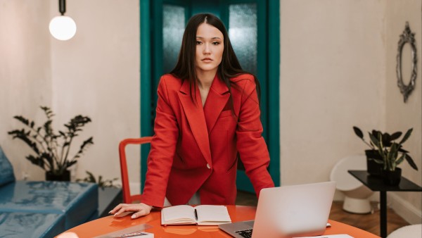 Businesswoman in red blazer standing behind a table