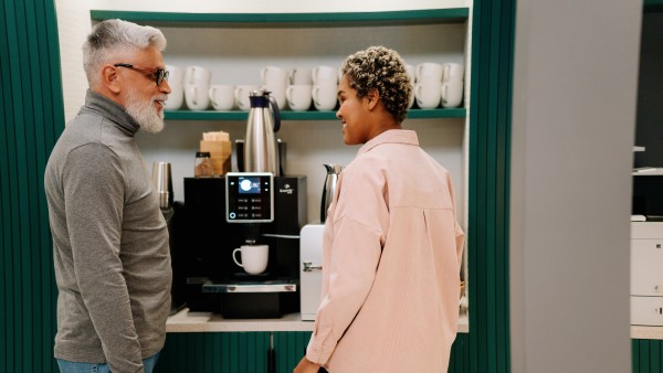 Colleagues having a conversation in front of the coffee station