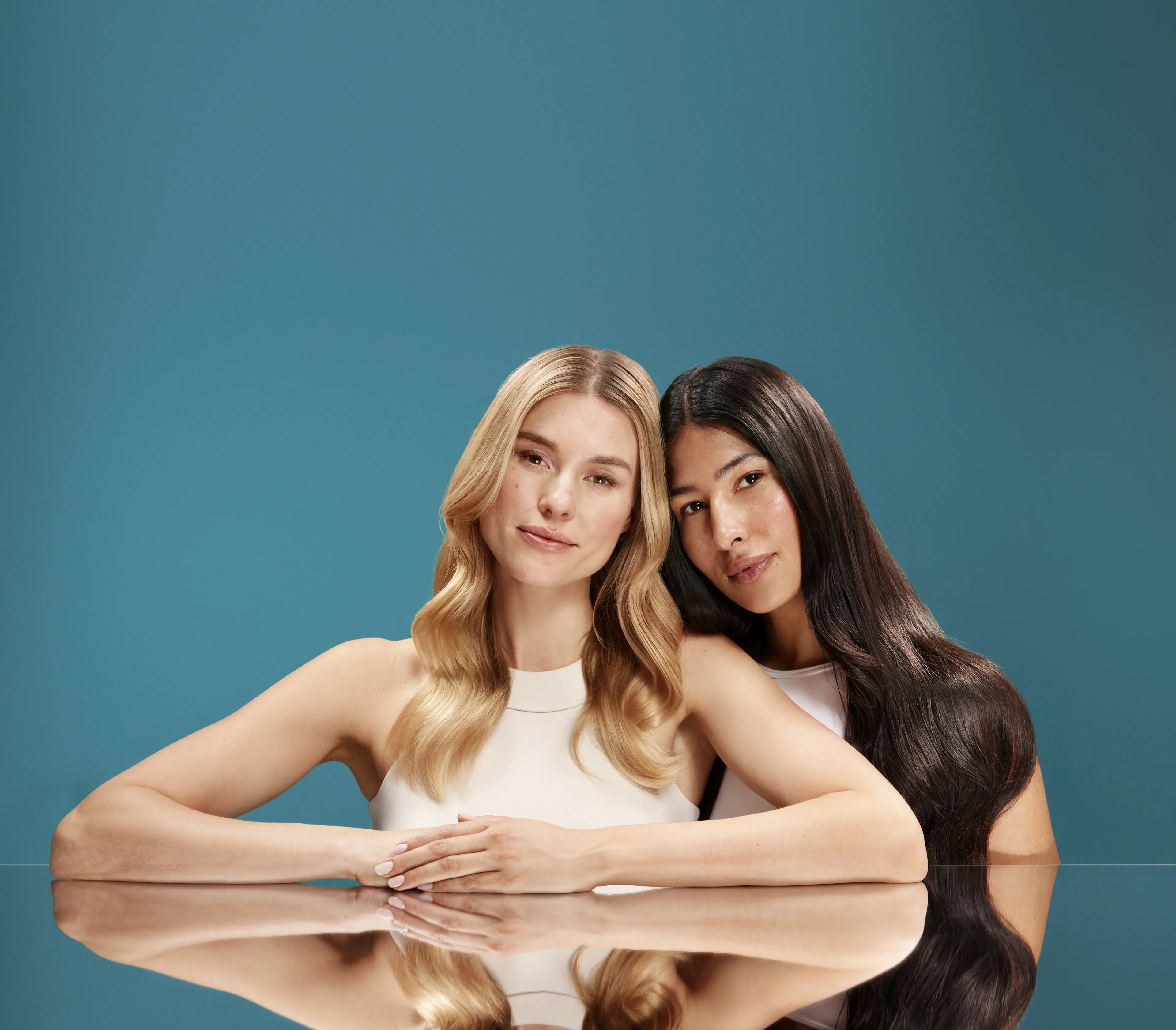 2 women with glossy hair after applying OGX® Lightweight Hair Oils