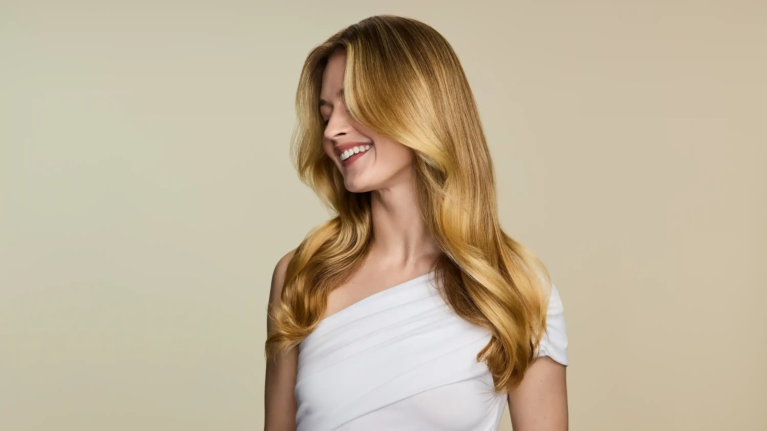 Smiling woman with straight hair after using OGX® Beauty products