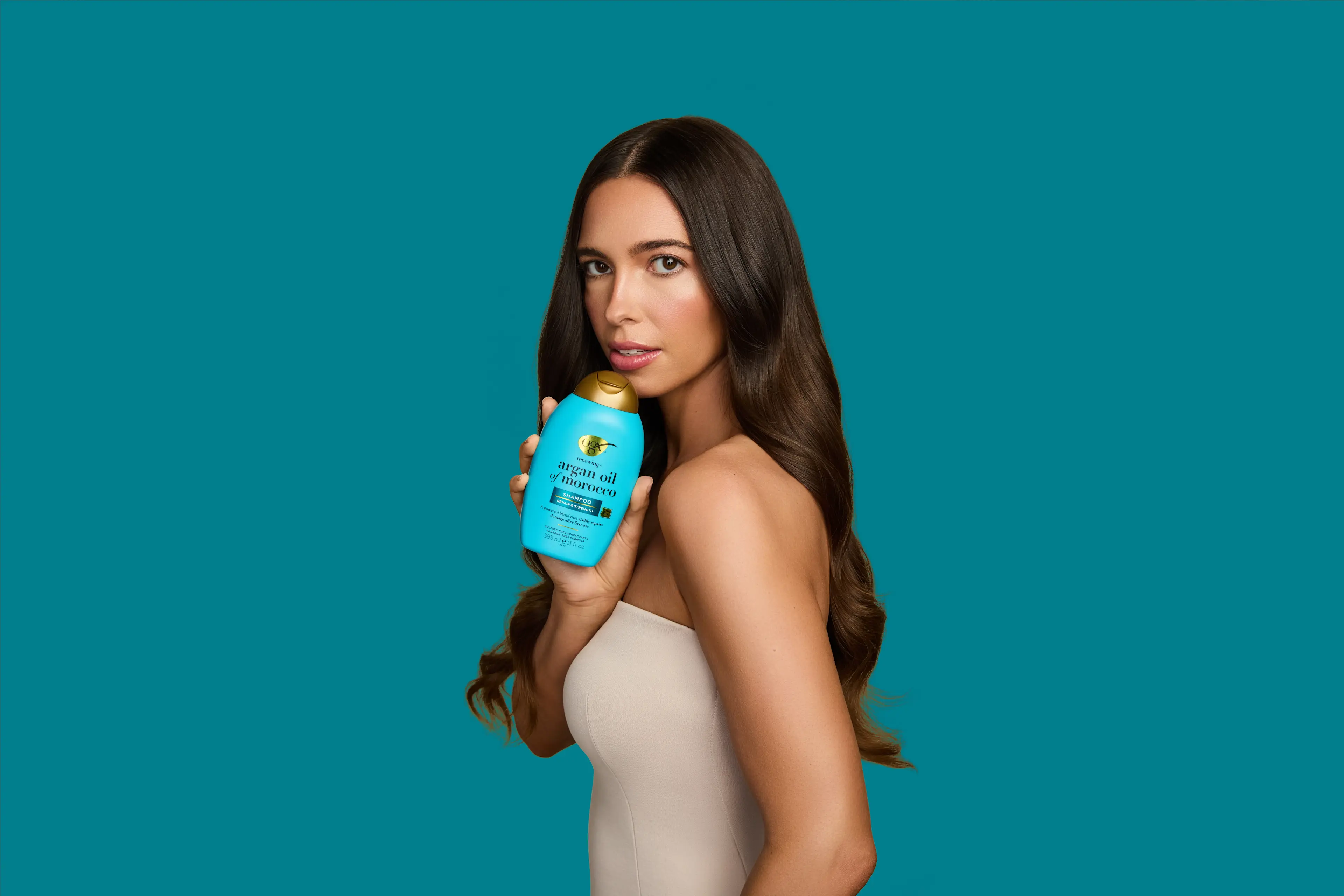 Woman with Shiny Hair holding OGX® Argan Oil of Morocco Shampoo