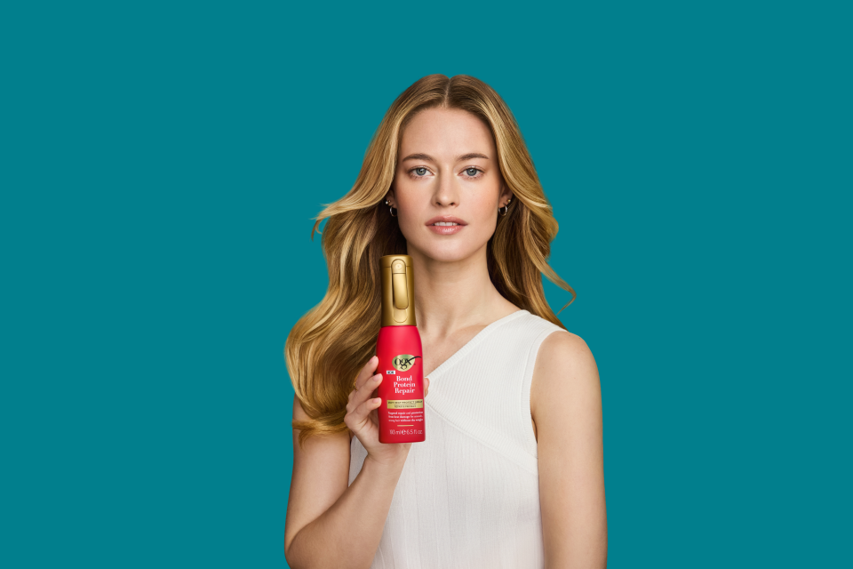 Image displaying woman holding OGX® Bond Protein Repair 450°F Heat Protect Spray